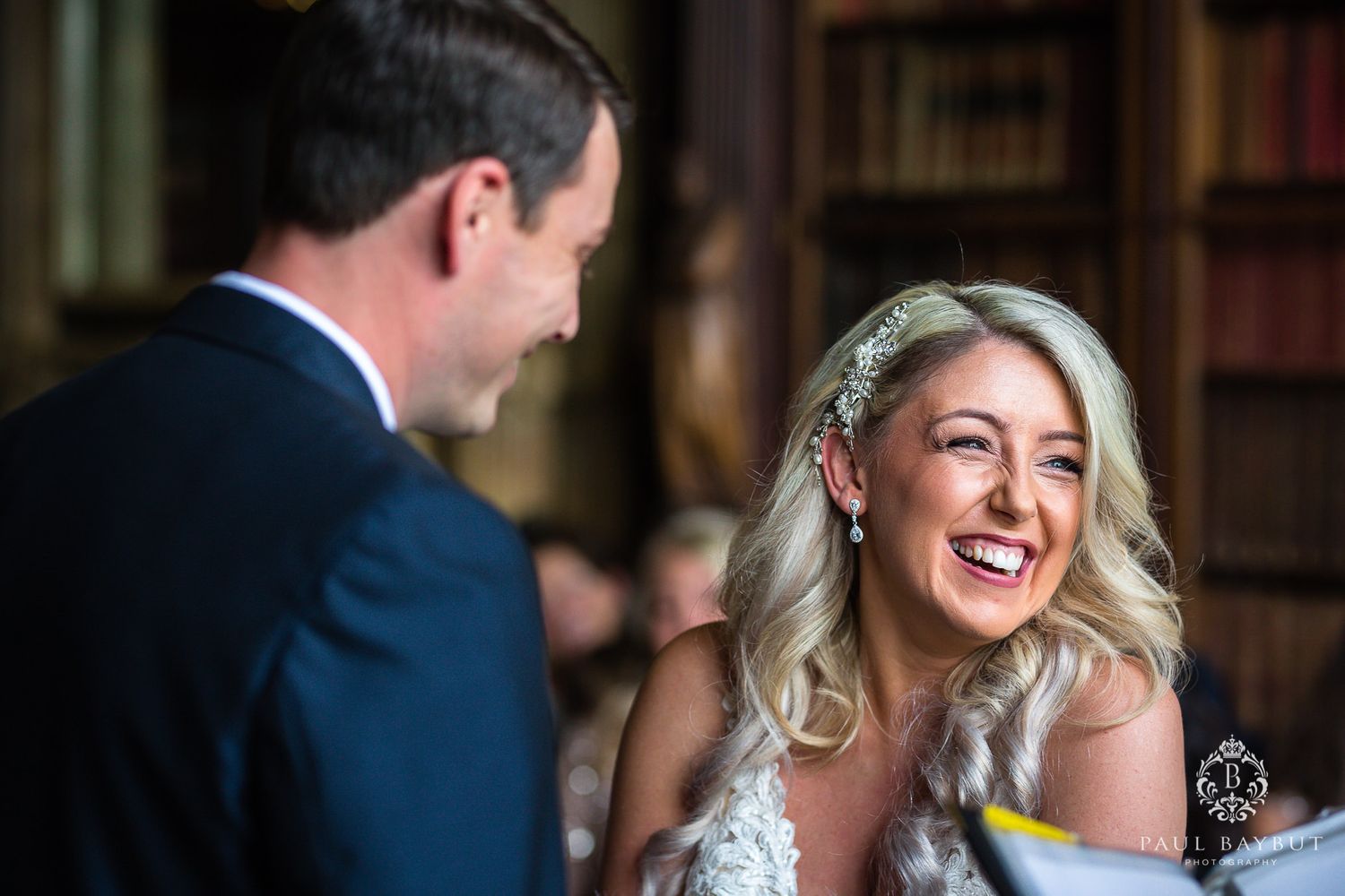A couple shares genuine laughter during their library wedding ceremony.