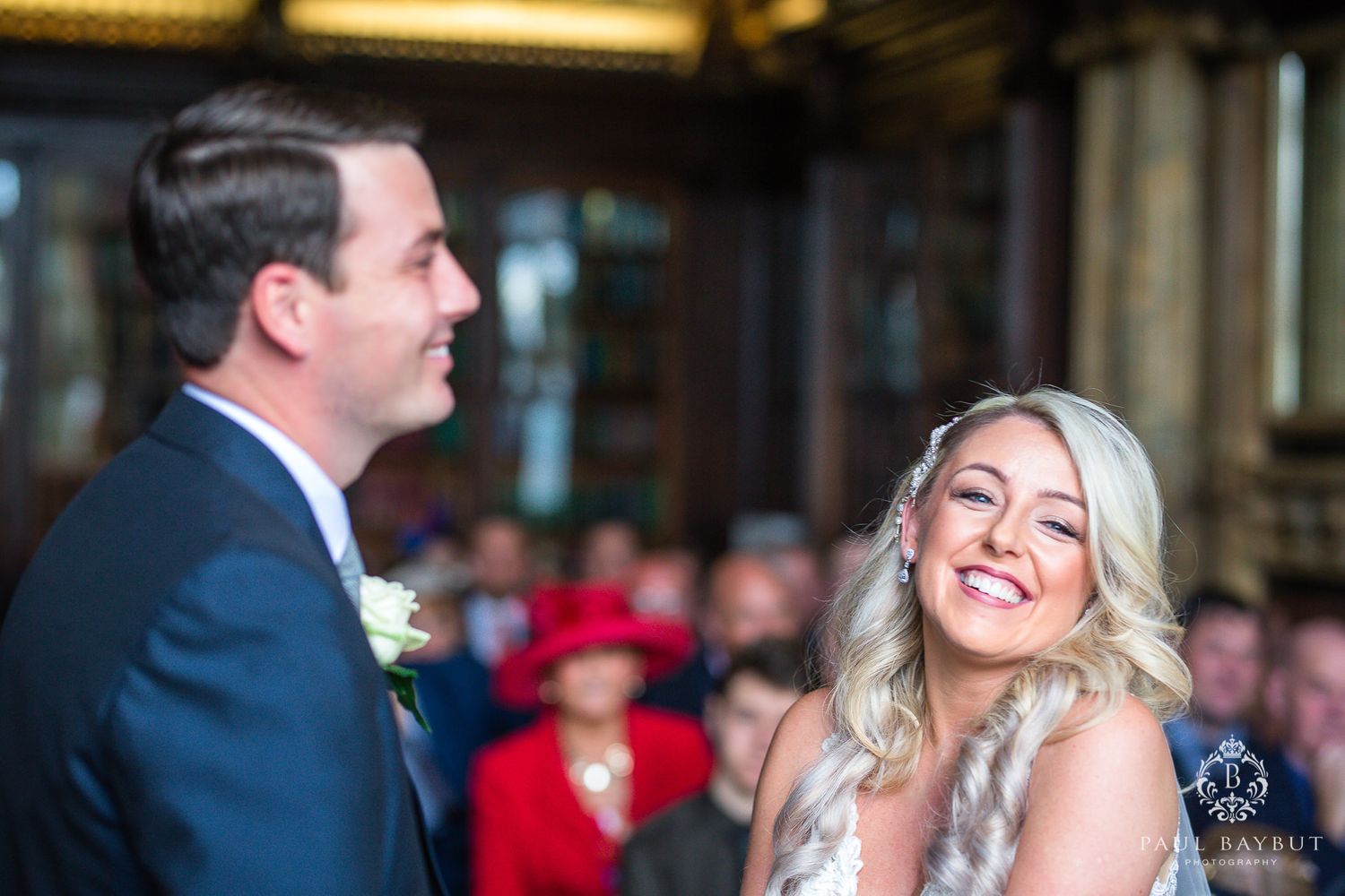 A joyful moment shared between a couple during their wedding ceremony in an ornate library setting.