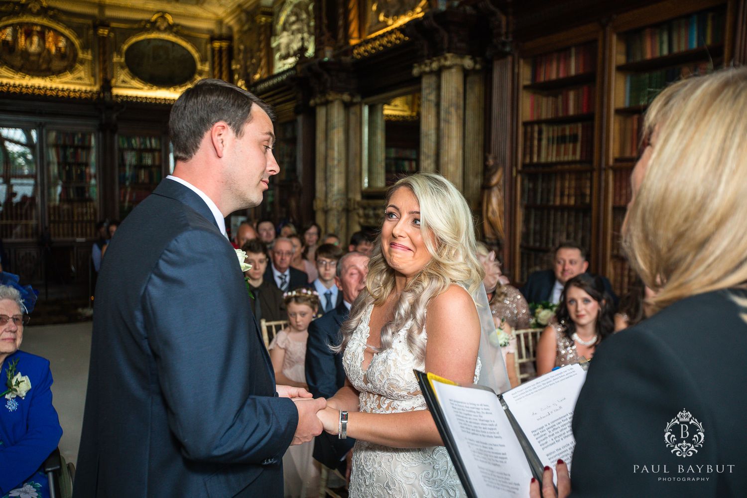 Exchange of rings during an intimate library wedding ceremony with book-lined walls.