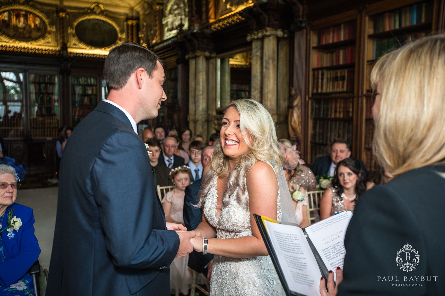 Happy couple sharing emotional moments during their wedding ceremony in a historic library.