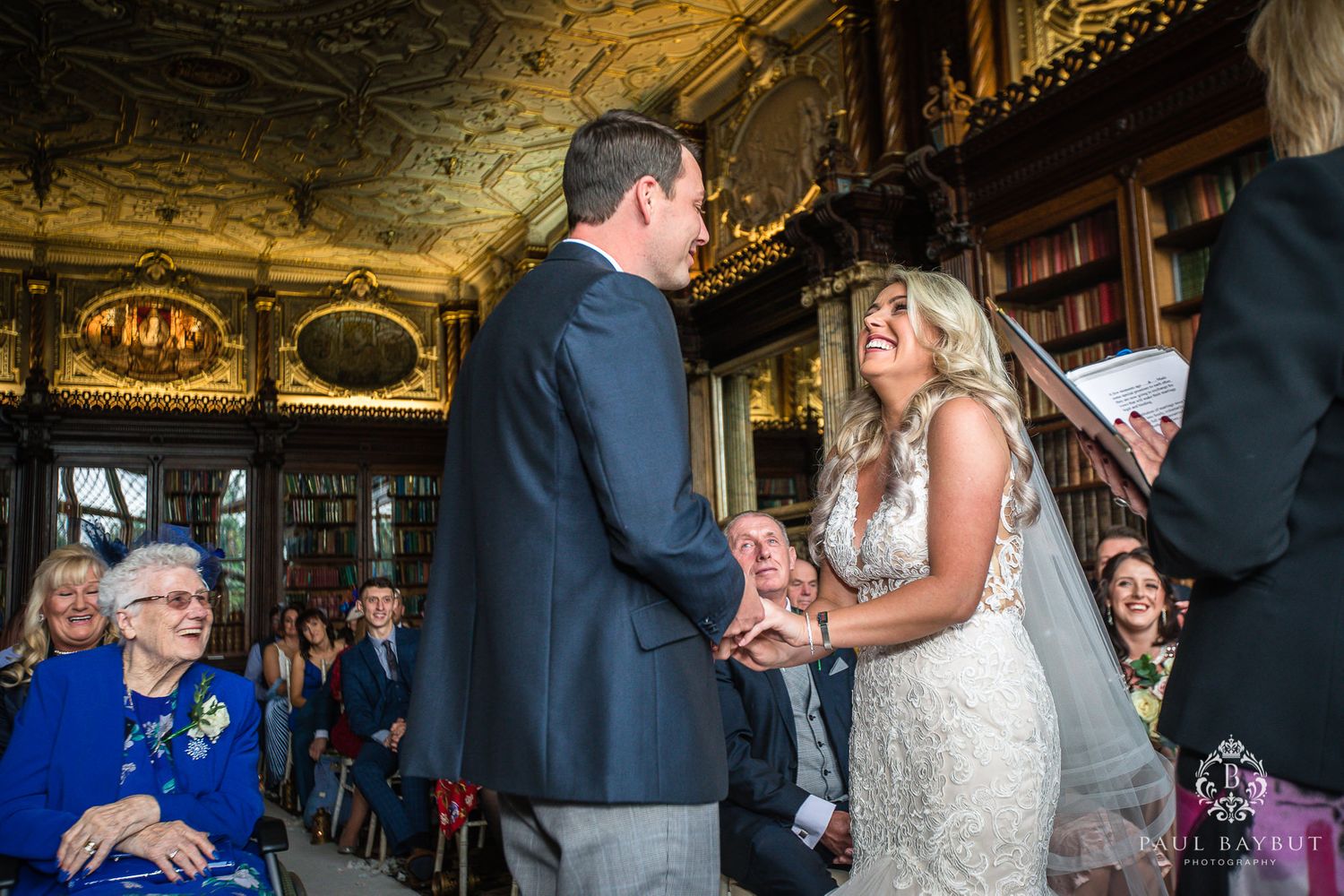 Couple exchanges vows during intimate library wedding ceremony with guests watching.