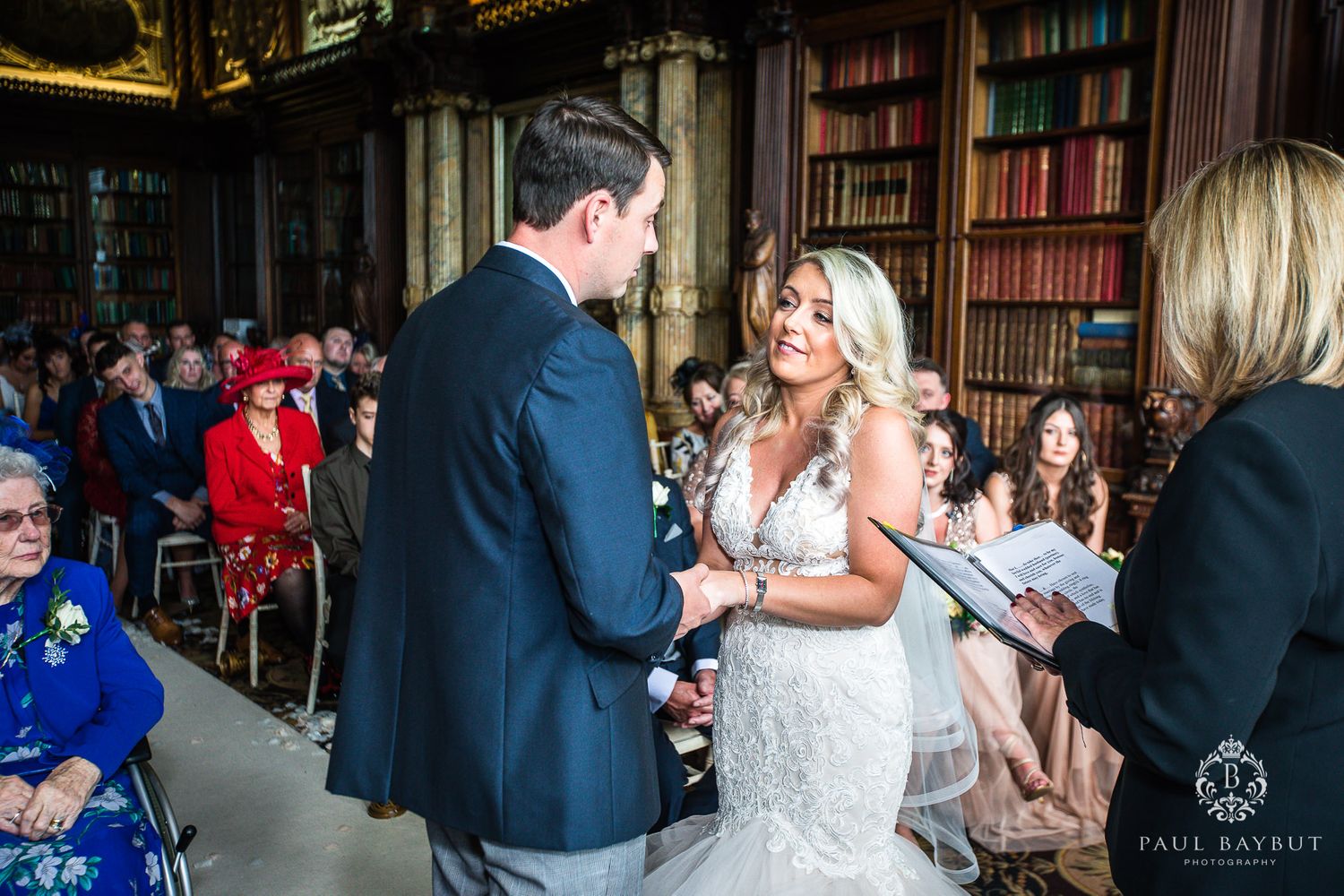 Emotional wedding ceremony moment captured in elegant library setting.