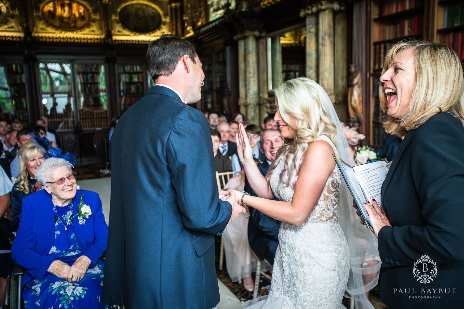 Joyful moment during library wedding ceremony with guests looking on.