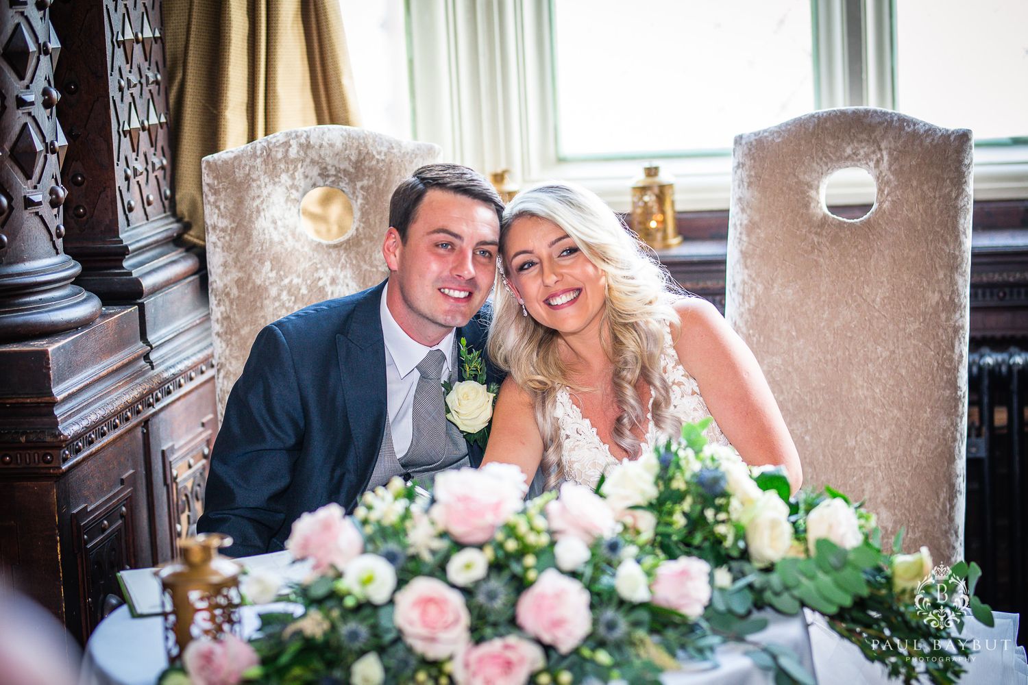 An elegant wedding reception table features beautiful pink rose centerpieces in a historic venue.