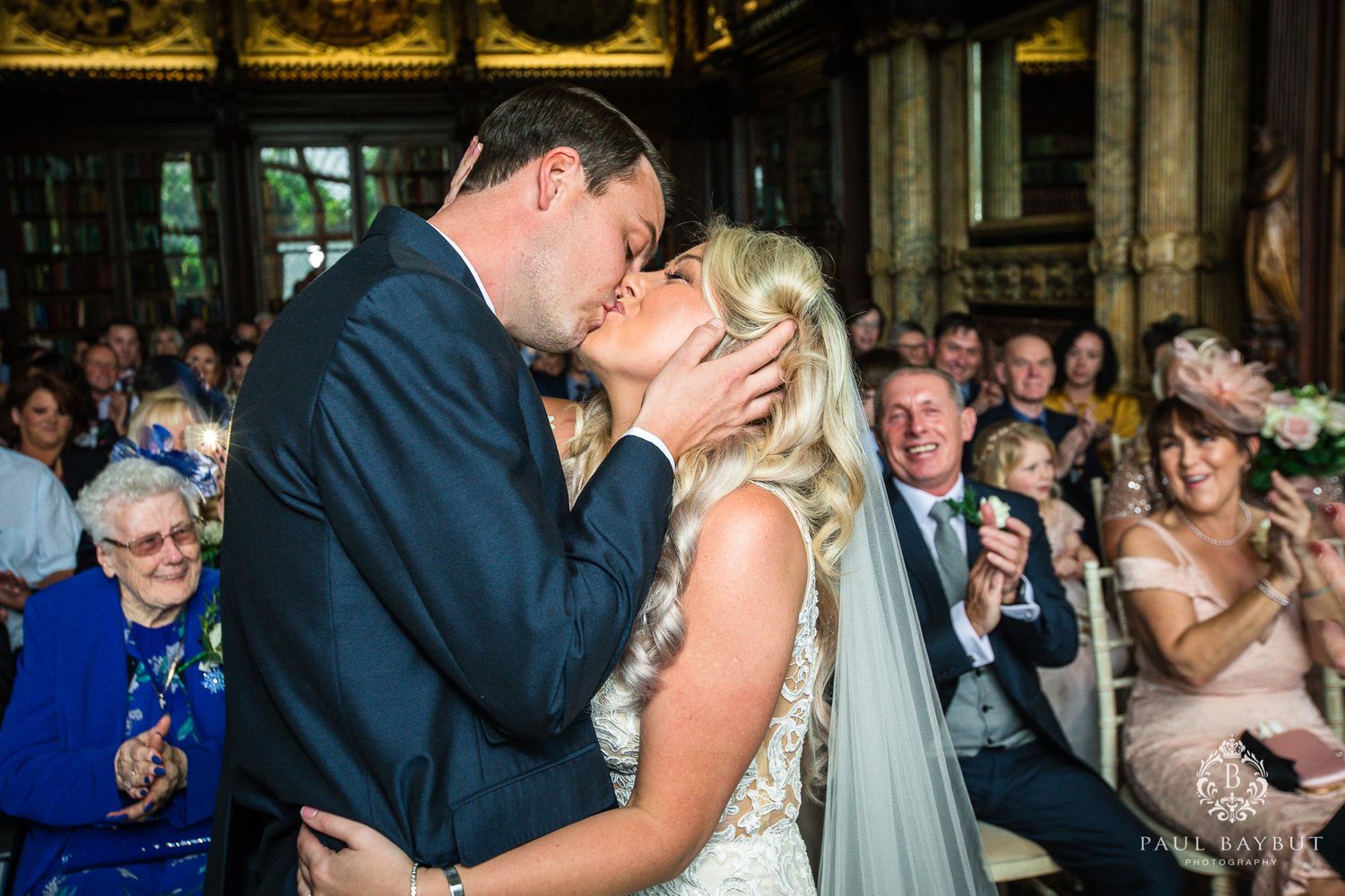 Guests applaud during an intimate wedding ceremony in a historic library setting.