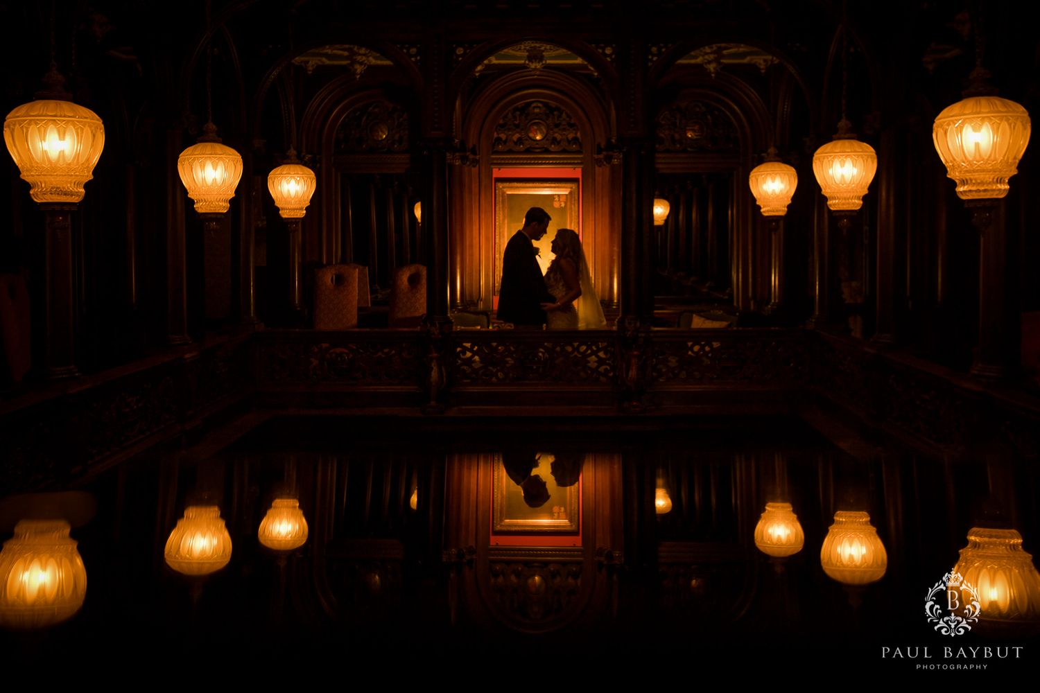 Dramatic silhouette against warm glowing lanterns creates romantic wedding portrait.