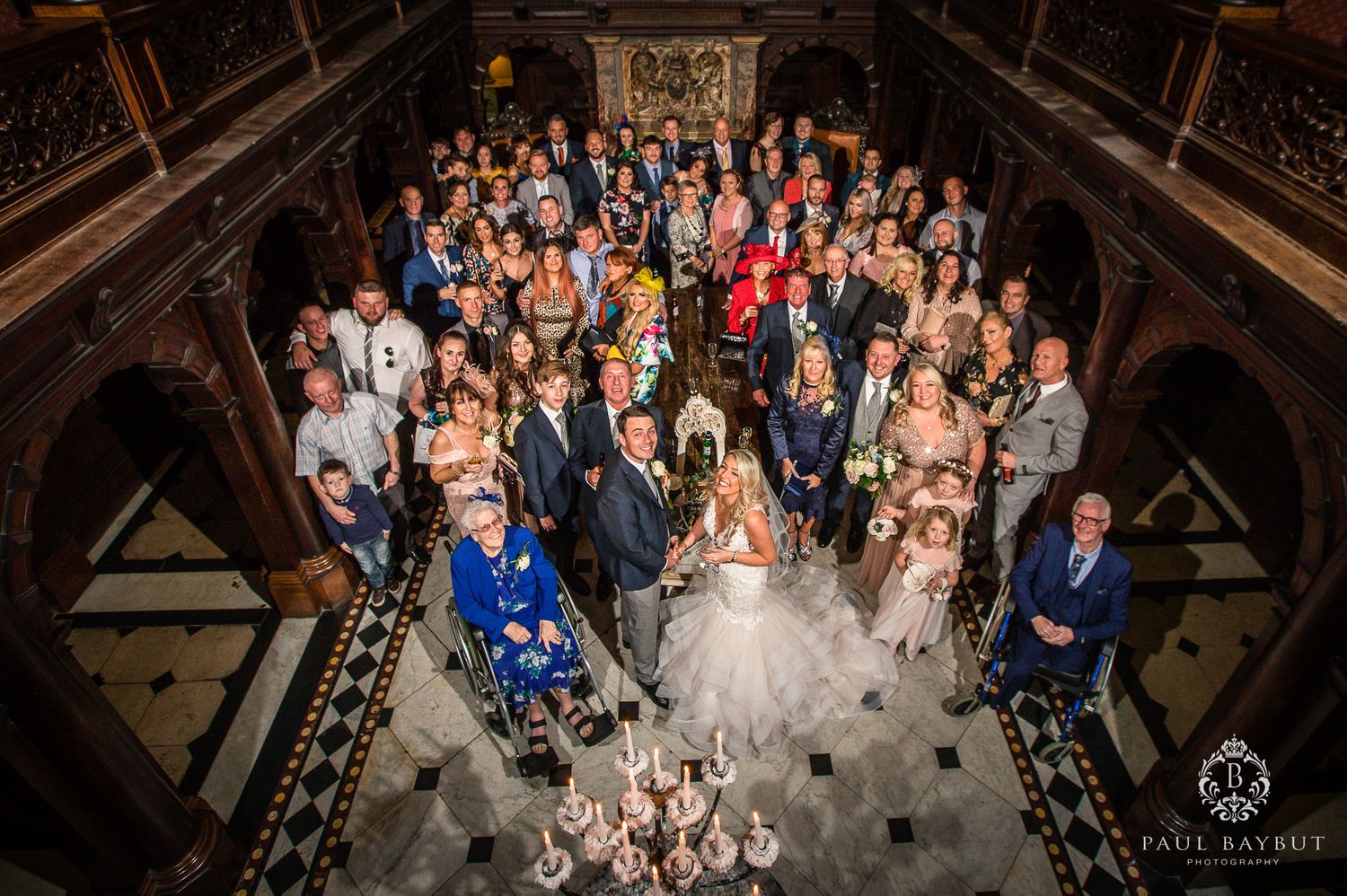 Large group wedding photo taken from above in an elaborate historic venue.