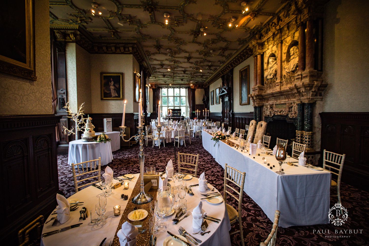 A formal banquet hall set for a wedding reception with white linens and classic wooden chairs.