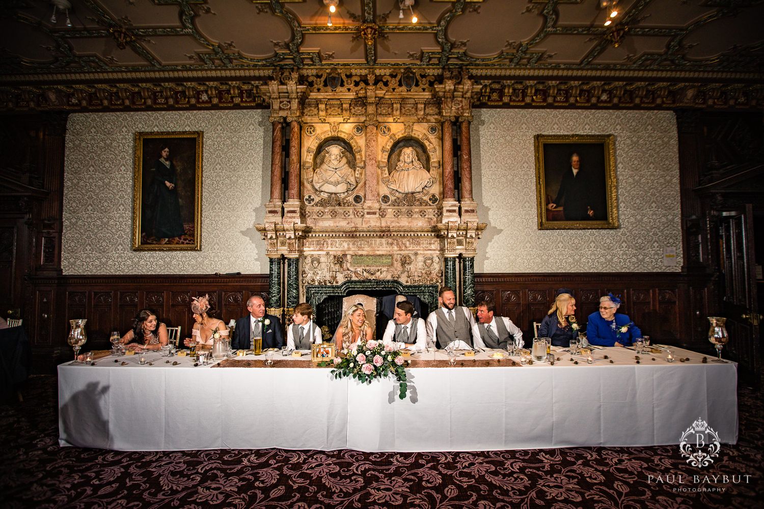 A traditional wedding reception head table arrangement in an ornate historic dining room.