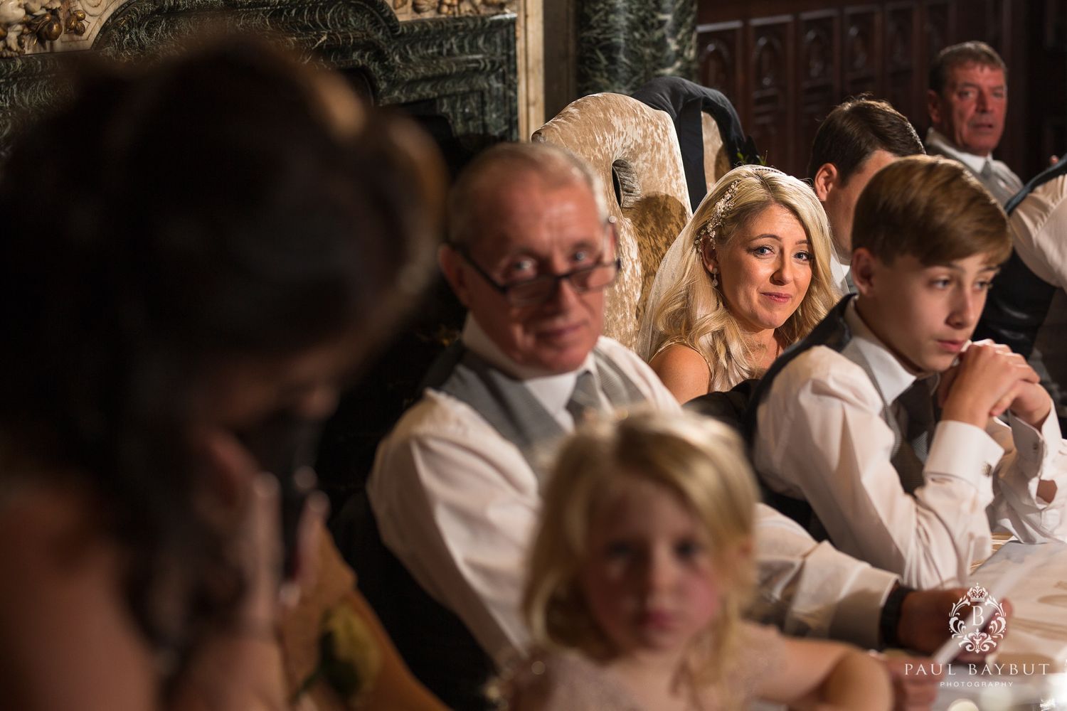 Wedding reception guests seated at an elegant banquet table sharing joyful reactions.