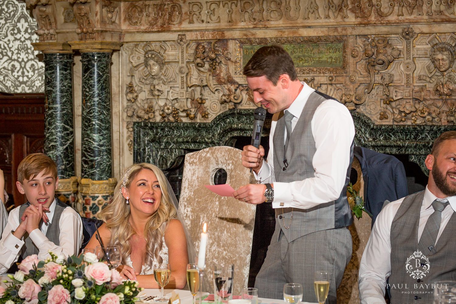 Reception dinner moment with laughter shared around an elegantly decorated table in a historic venue.