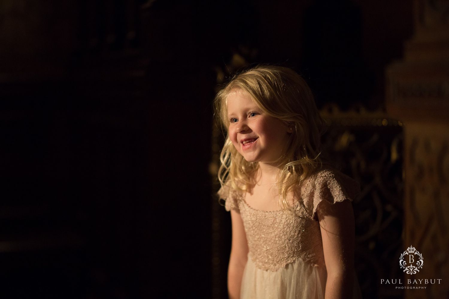 Young attendee in a delicate dress smiles during an evening celebration.