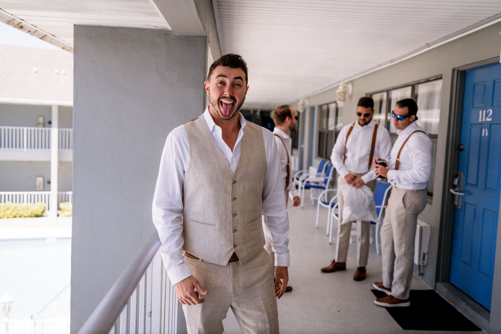 Wedding party in light colored attire standing in a hotel hallway.