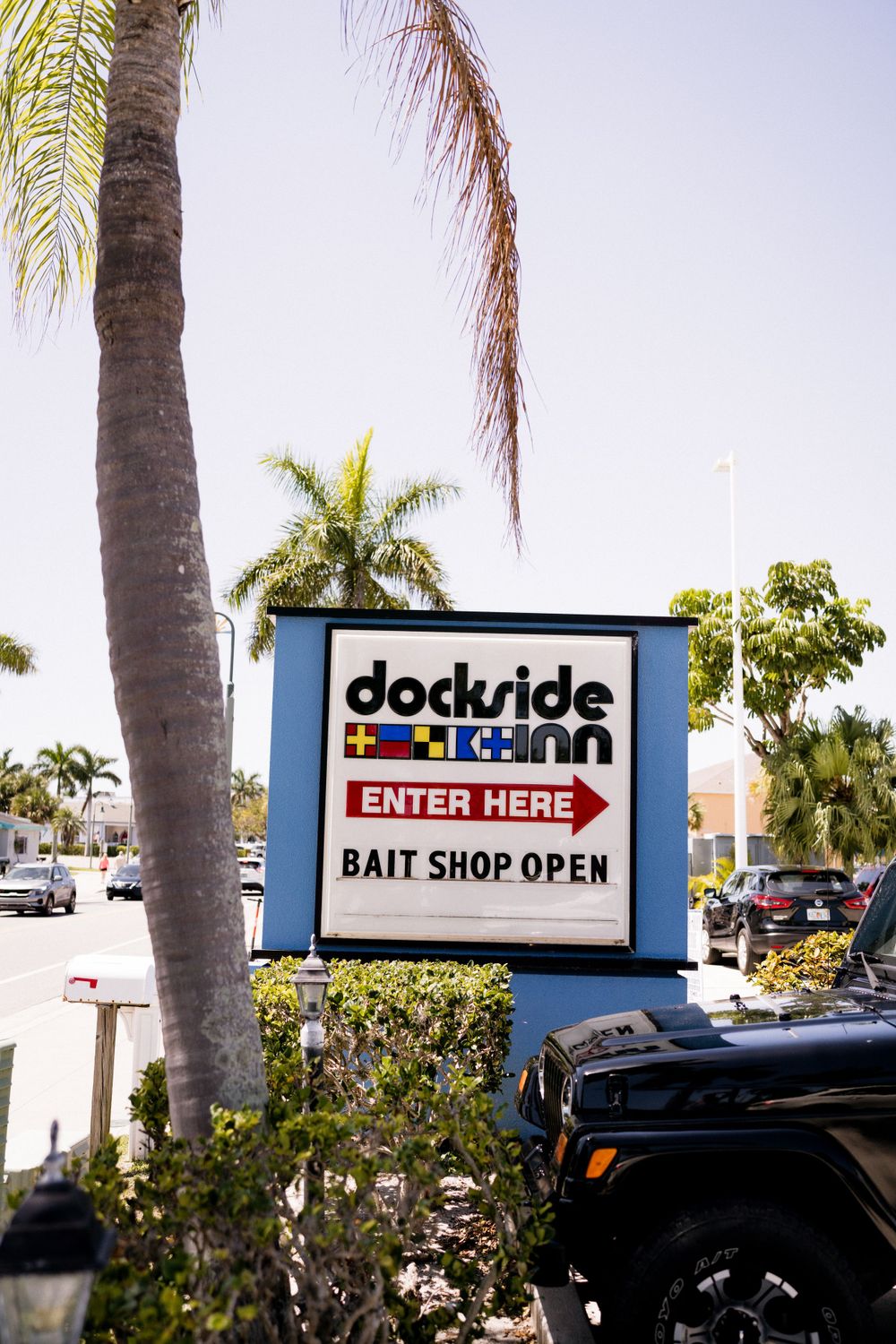 A Dockside bait shop entrance sign with palm trees in Florida.