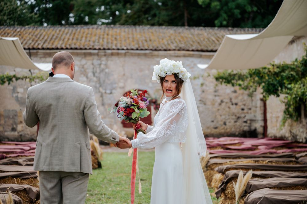 Wedding couple dancing outdoors against a rustic stone wall backdrop.