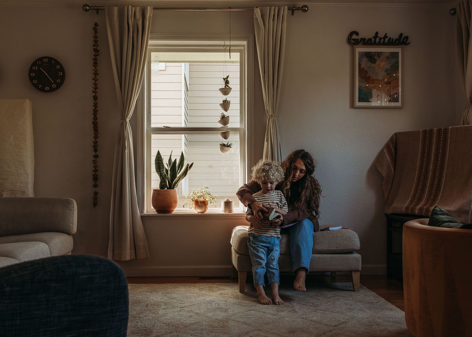 A warm family moment by a window with natural light streaming in and potted plants on the windowsill.