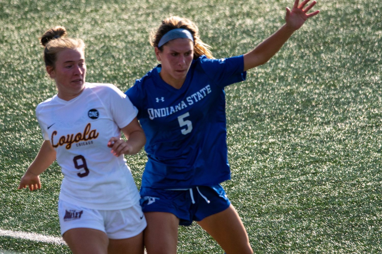 Soccer players from opposing teams challenging for ball during intense match.