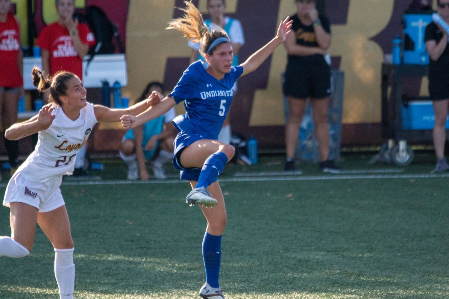 Competitive soccer match between teams in blue and white uniforms on artificial turf.