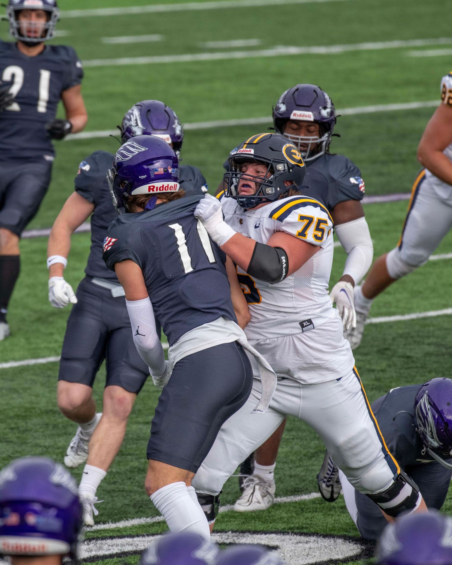 Football players engage in blocking and tackling action during a competitive game.