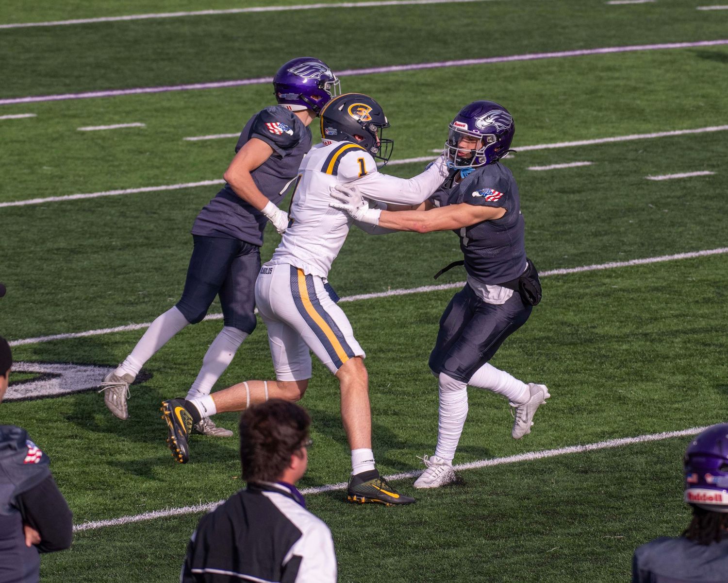 Football players from opposing teams collide during game play on field.