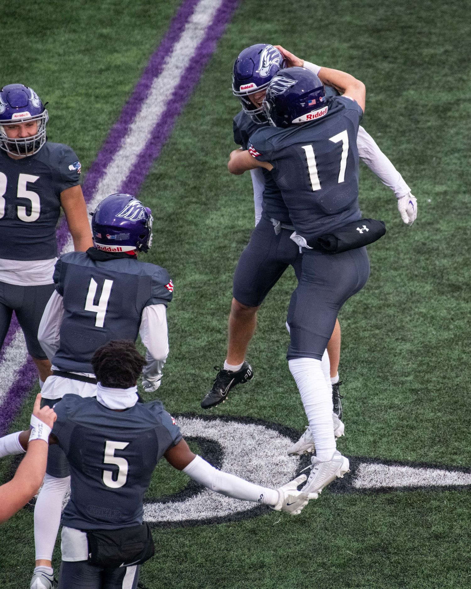 Football players in purple uniforms celebrating on field during game.