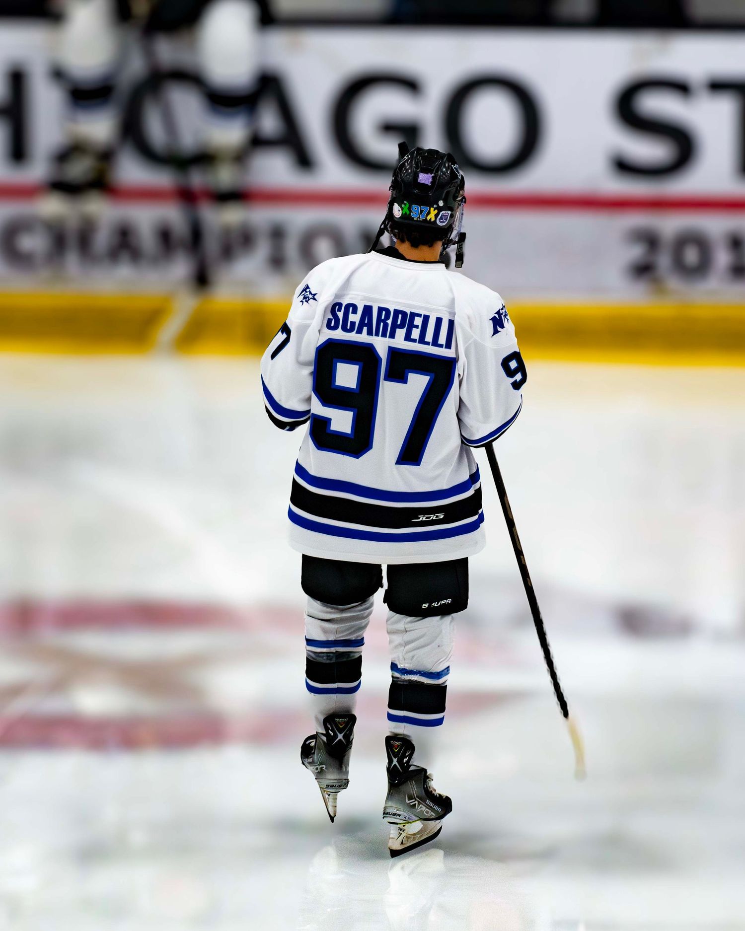 Hockey player wearing number 97 in white jersey skating on ice during a game.