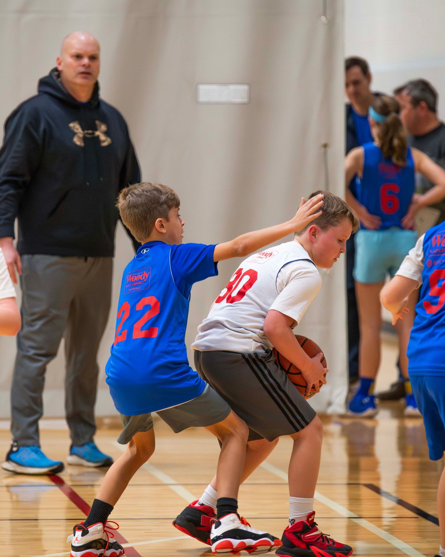 Young athletes practicing basketball drills in a gymnasium with blue and white uniforms.
