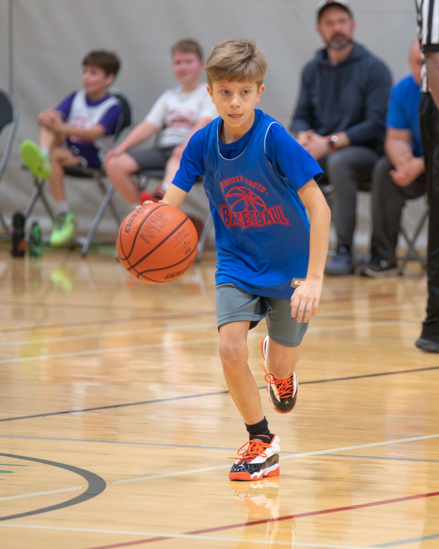Children dribbling basketballs during a youth sports practice in a gymnasium.