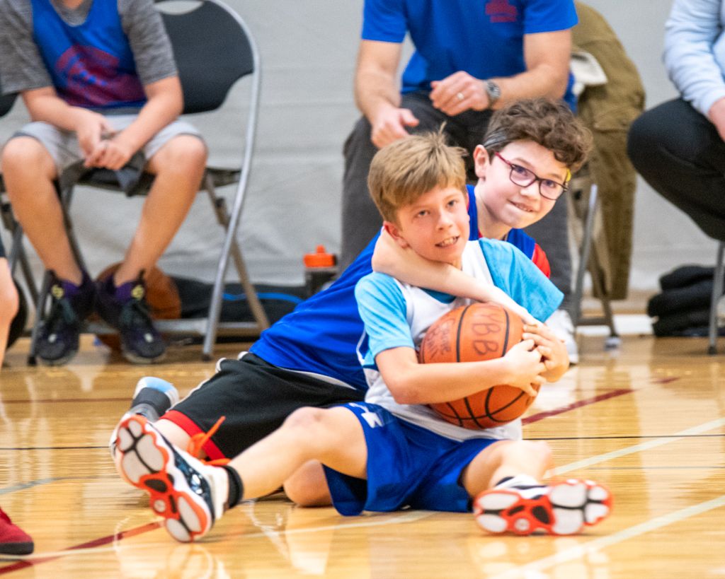 Basketball players diving for loose balls during an indoor practice session.