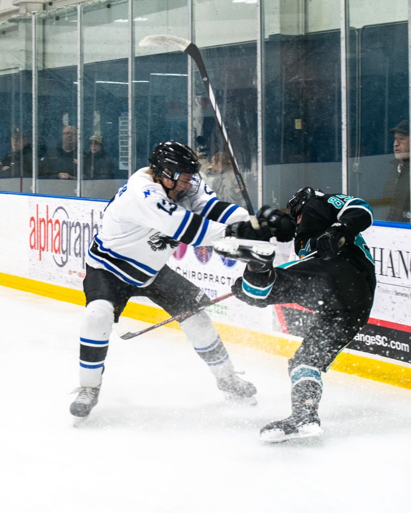 Hockey players collide and spray ice during an intense game sequence.