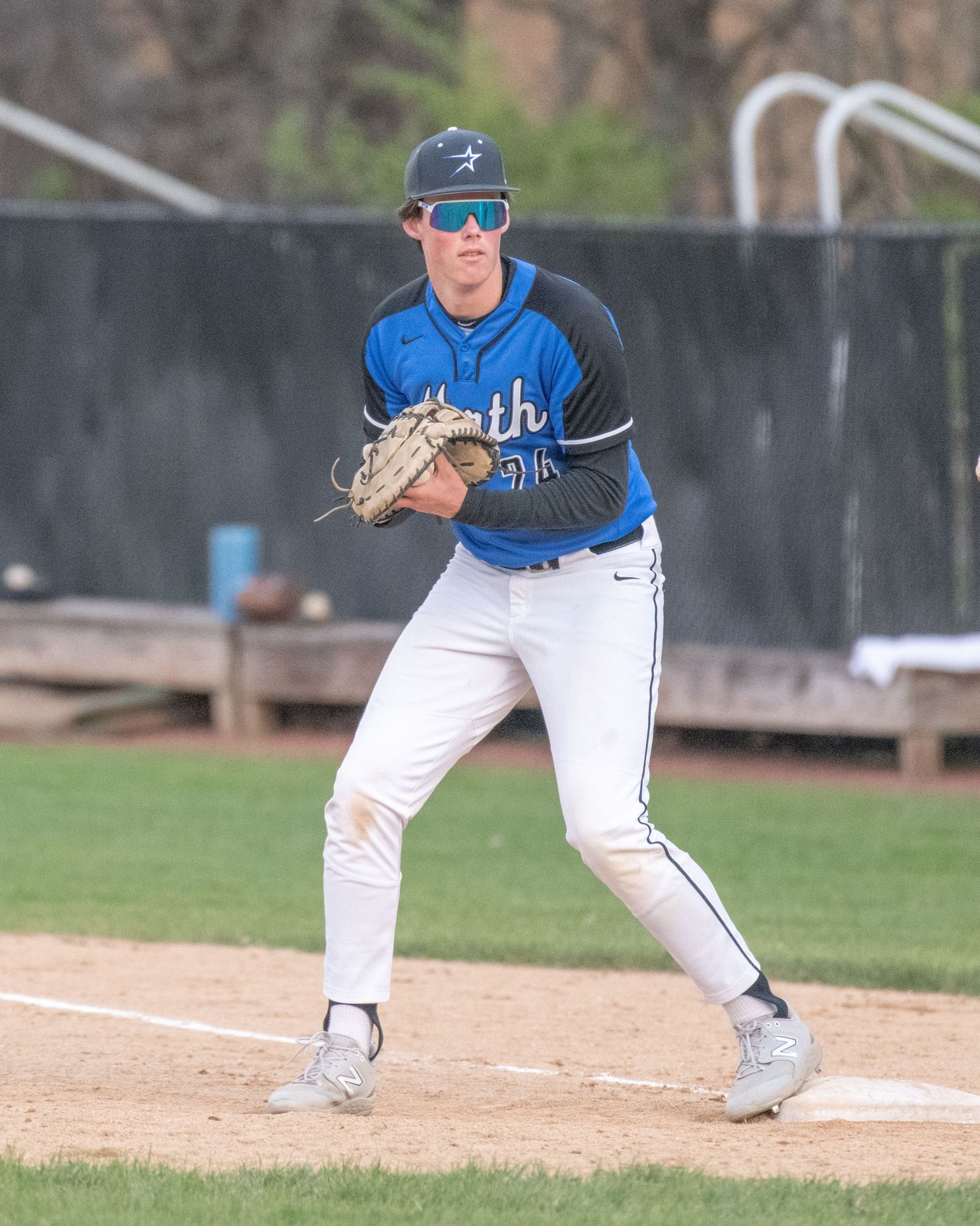 Baseball player in blue uniform preparing to pitch on mound.