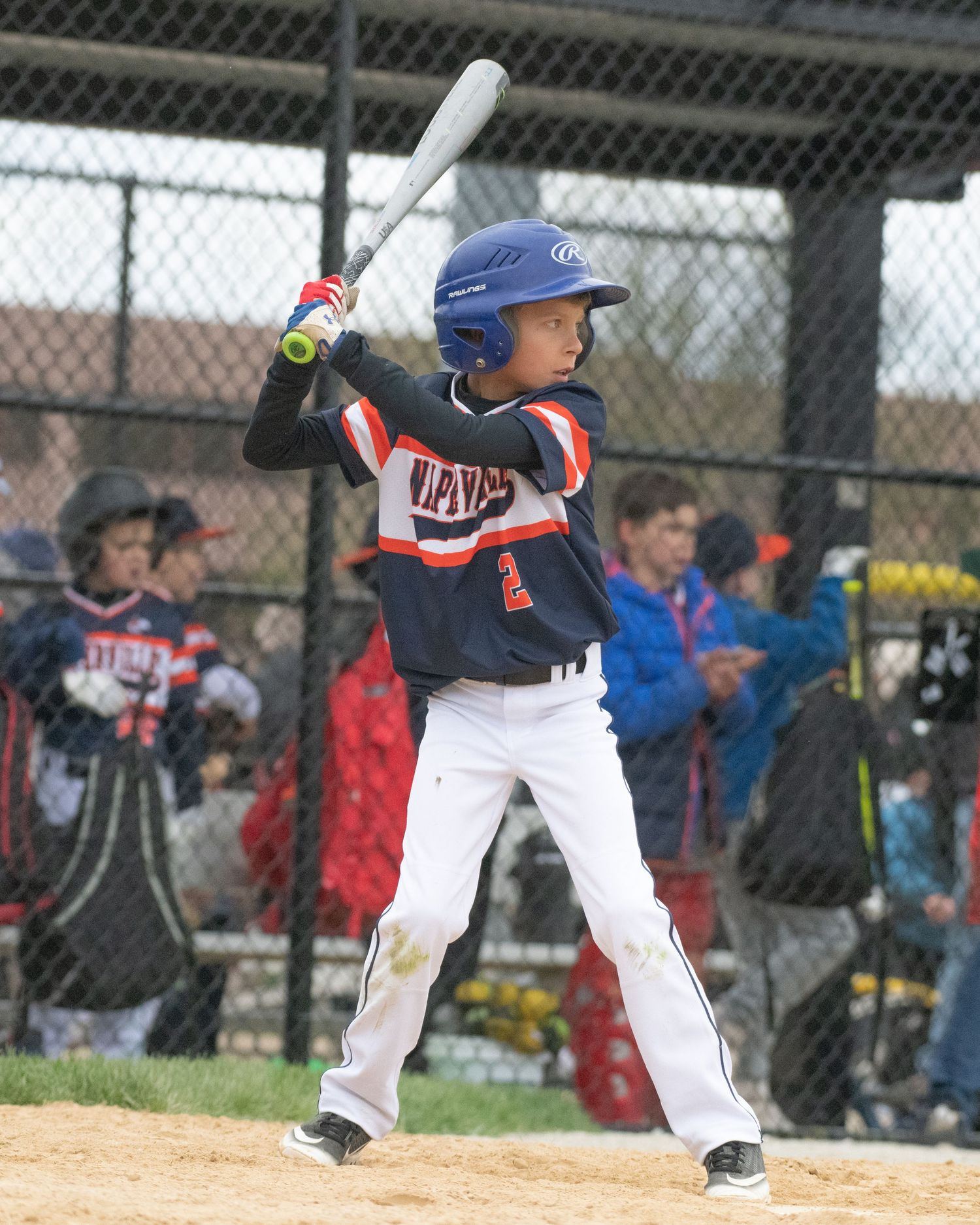 Youth baseball players in blue and white uniforms practicing batting at a baseball field.