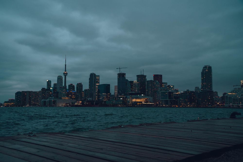 Toronto skyline at dusk with moody clouds over Lake Ontario.