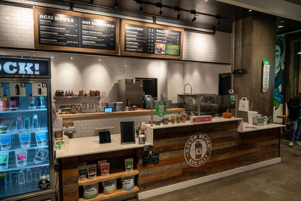 Modern coffee shop counter with menu board and rustic wood paneling.