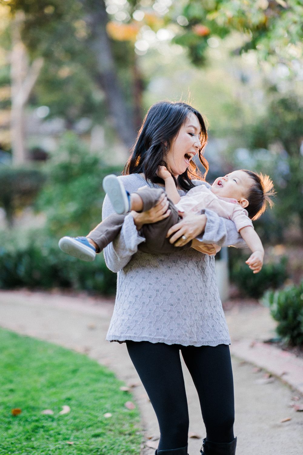 A joyful moment shared between parent and baby outdoors in a garden setting with natural lighting.
