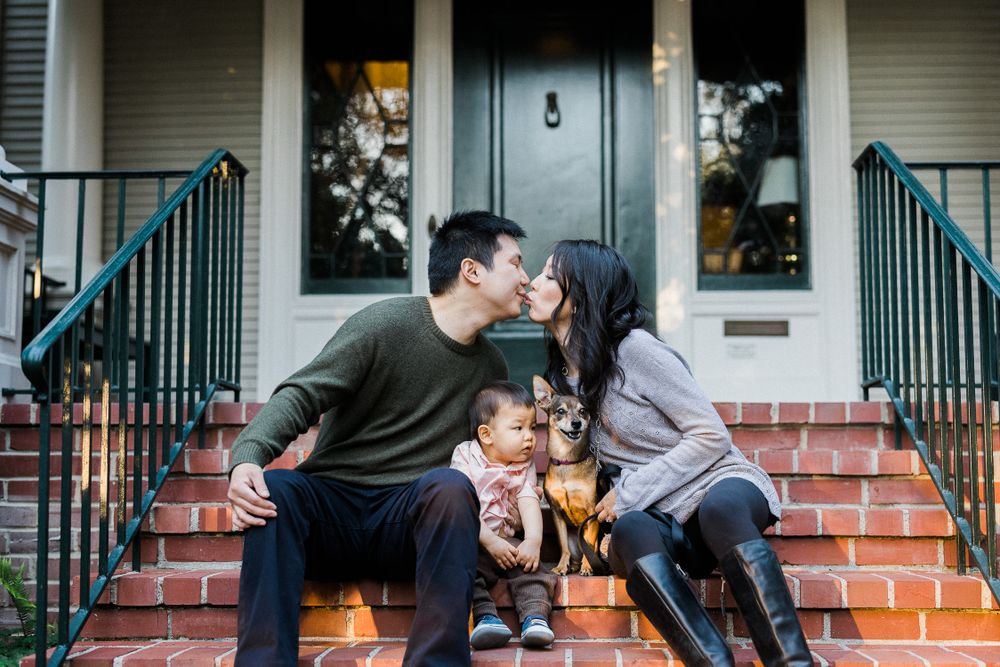 Family sharing intimate moment on brick steps of urban home with iron railings.