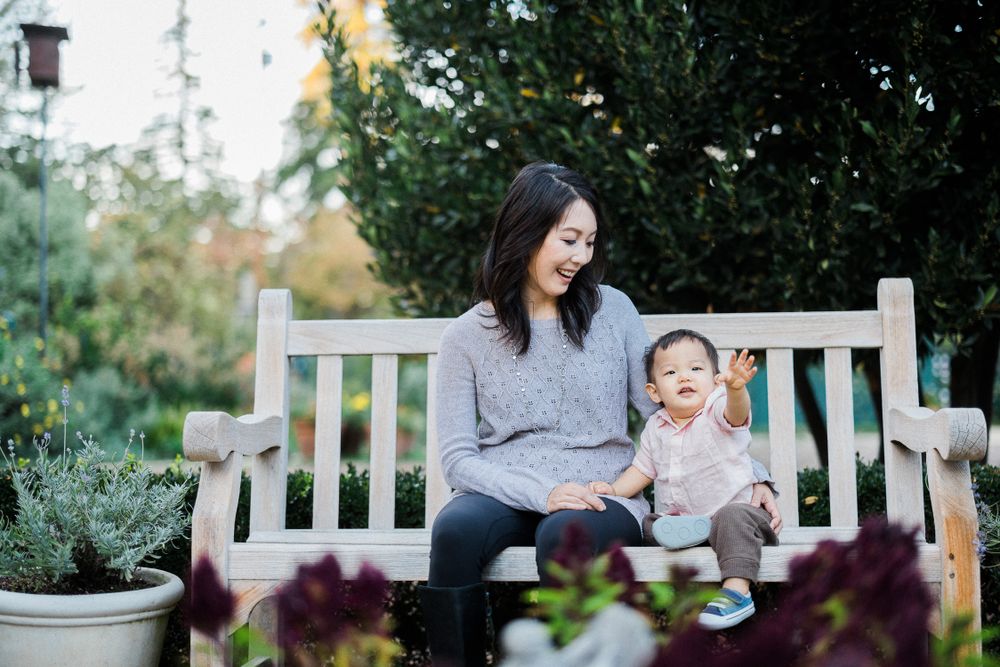 A heartwarming moment as parent and child share laughter on a garden bench.