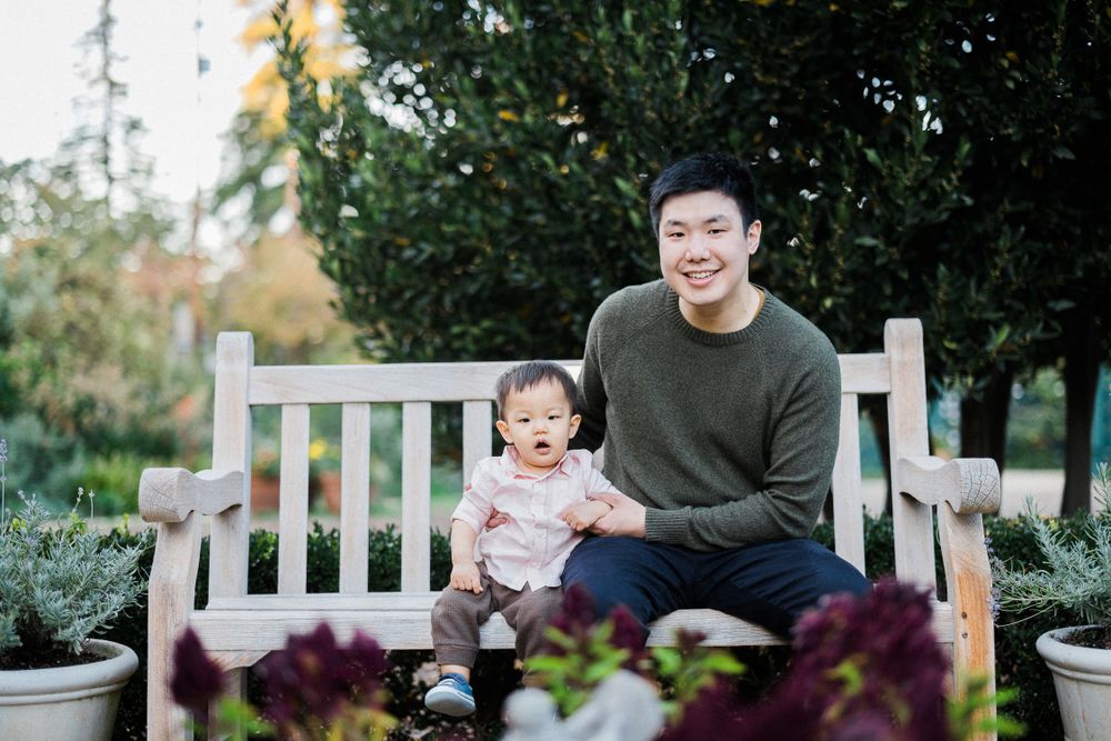 A tender moment between parent and child sitting on a wooden bench in a garden.