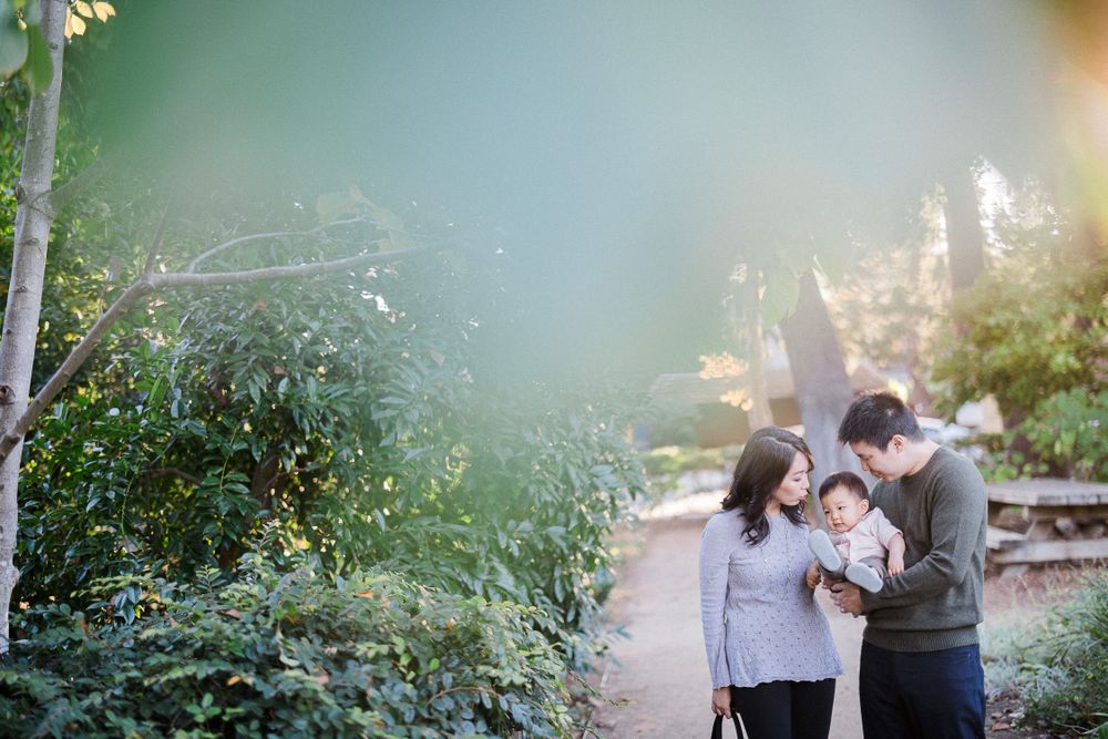 A family enjoys a tender moment together on a garden path surrounded by lush greenery.