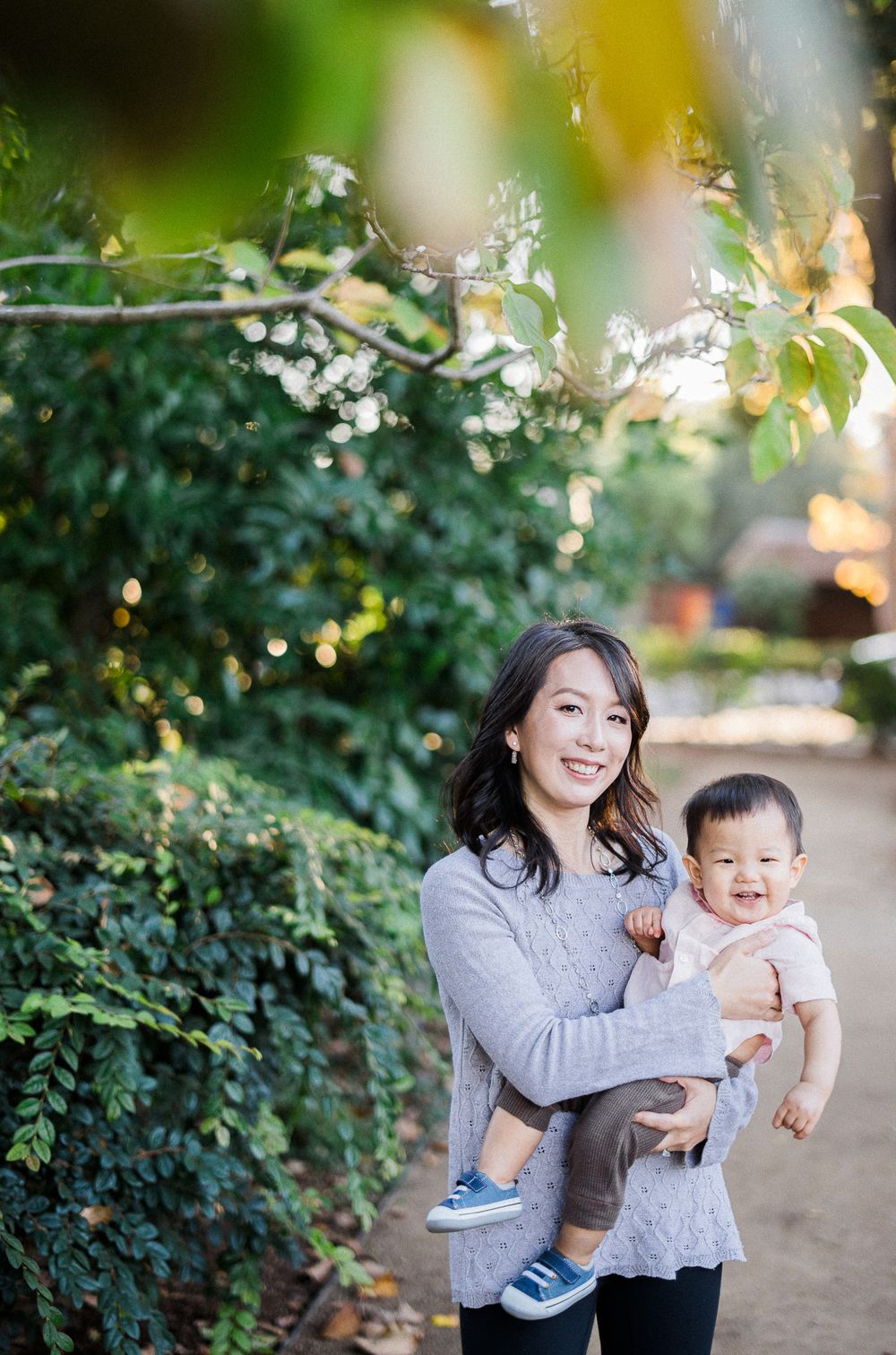 A touching outdoor portrait of parent and child against blooming garden foliage.
