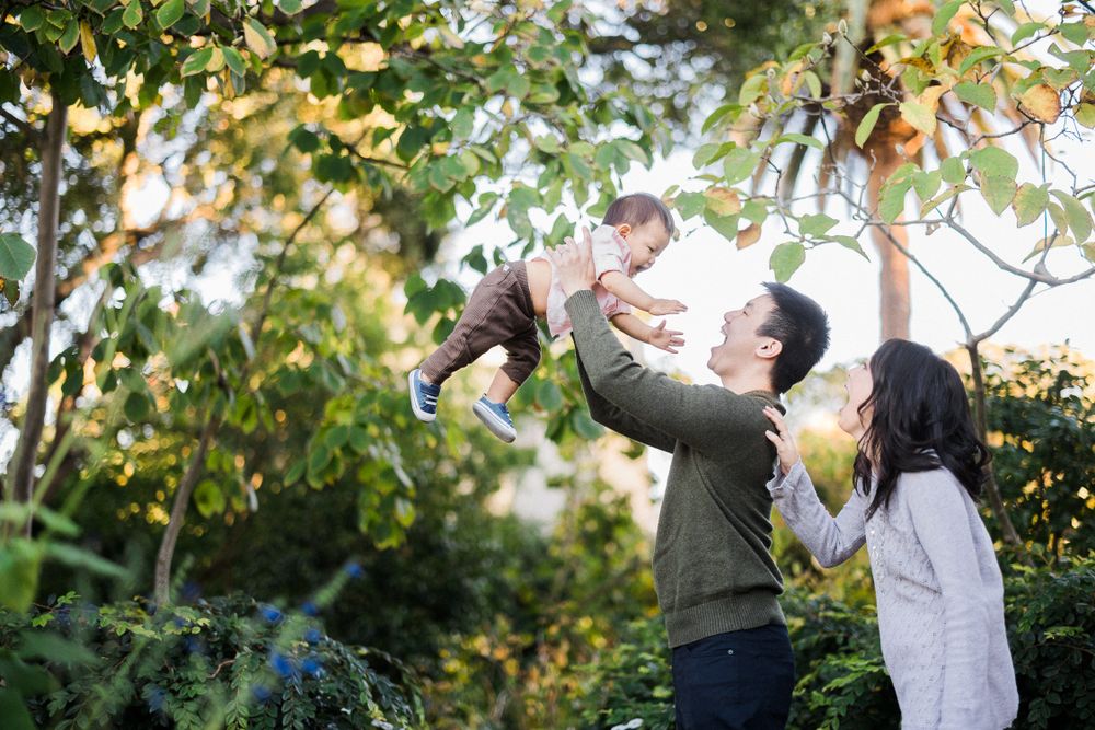 A joyful family moment captured in a sunlit garden with playful interactions.