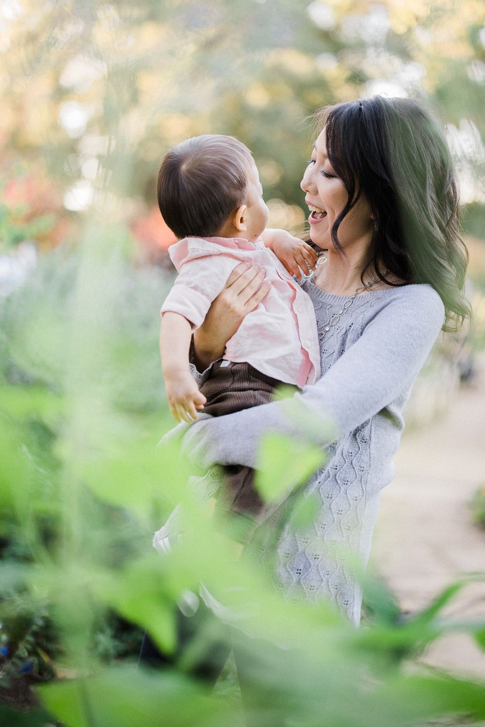 Intimate portrait of parental bonding in a sunlit garden with soft bokeh effects.
