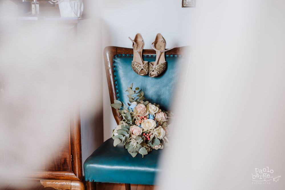 Bridal shoes and bouquet arranged on turquoise vintage chair.