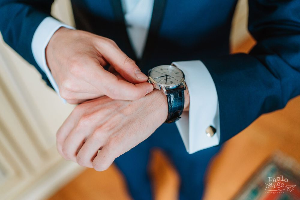 Close-up of hands adjusting a watch on formal suit sleeve.