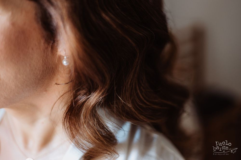 Close-up of elegant wavy brown hair with pearl earring detail.