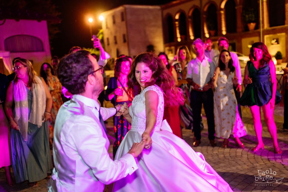 Wedding celebration on a dance floor illuminated by vibrant pink lighting.