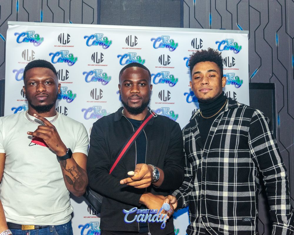 Three men posing together in front of Sweet Candy event backdrop.