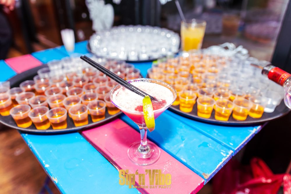 Colorful display of cocktails and shot glasses arranged on a vibrant bar table.