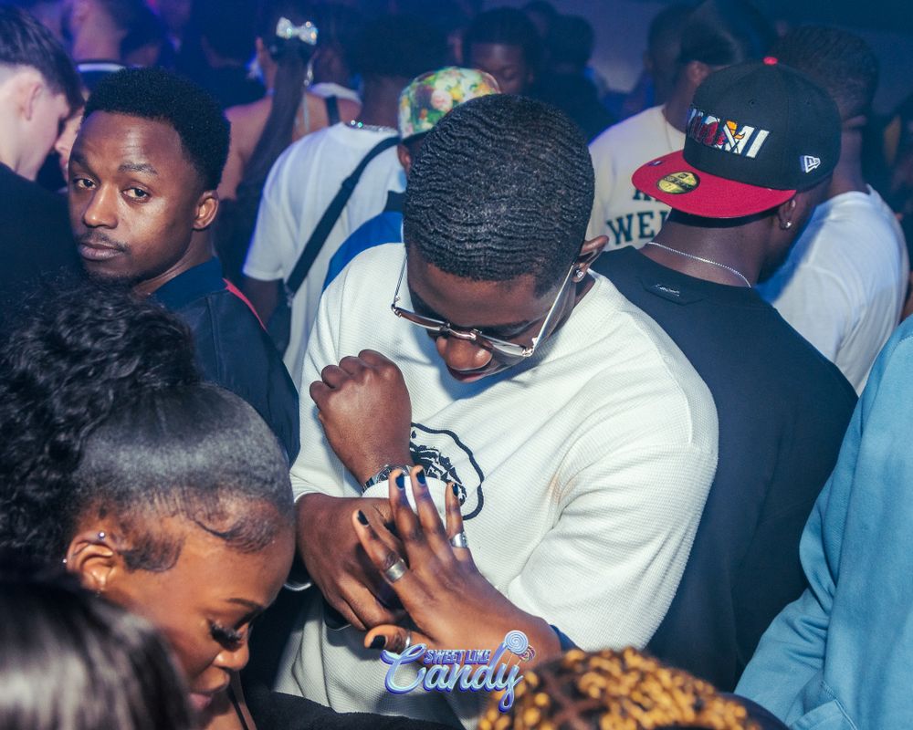 People socializing and dancing at a crowded nightclub party event.