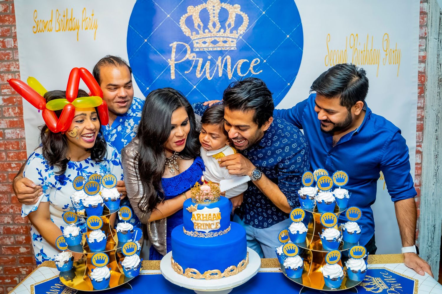 A festive birthday celebration with a blue royal-themed cake and decorations.